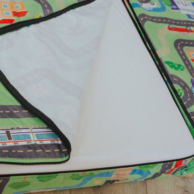Children's play mat with road patterns and a train design on a wooden floor.
